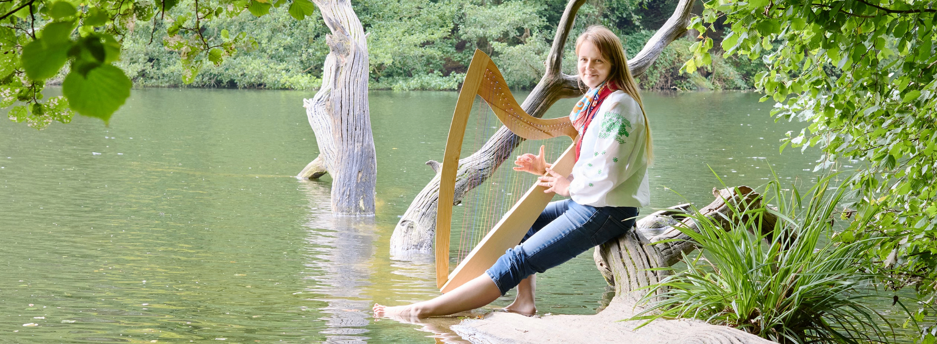 Morwenna Rose playing her Celtic harp by a lake